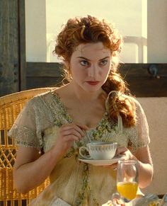 a woman sitting at a table with a bowl of food in front of her face