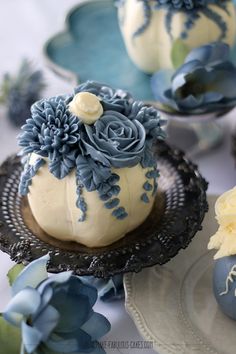 blue and white flowers decorate the top of some cakes on plates with other desserts in the background