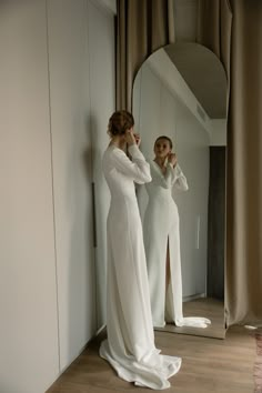 two women in white dresses are looking at their reflection in the mirror and brushing their teeth