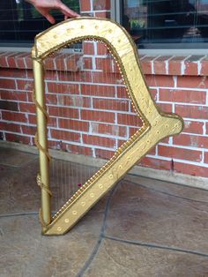 a gold colored harp sitting on the ground next to a brick wall