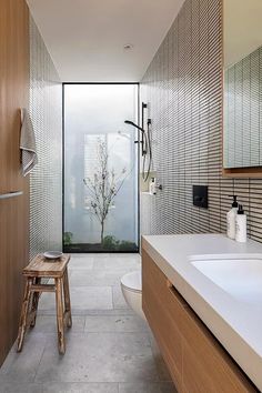 a modern bathroom with wooden accents and tile flooring, along with a walk in shower