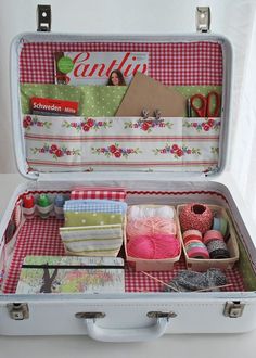 an open suitcase with yarn, scissors and other crafting items in it on a table