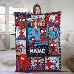 a woman holding up a quilt with spiderman pictures on it and name written in the center