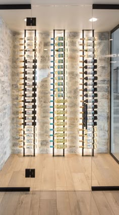 a wine cellar with glass walls and wooden flooring in front of a stone wall