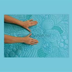 two hands touching each other on a blue background with an intricate flower design in the middle