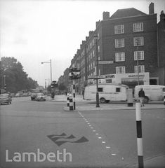 cars are driving down the street in front of tall buildings and traffic signs with arrows pointing to different directions