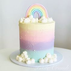 there is a rainbow cake with marshmallows on the bottom and white frosting