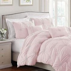 a bed with pink comforter and pillows in a room