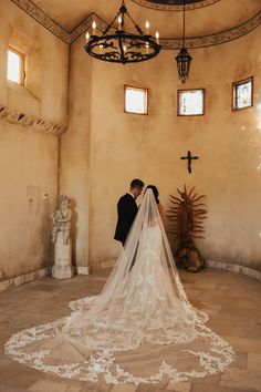 a bride and groom standing in front of the alter with their veil blowing in the wind