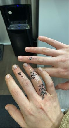 two hands with tattoos on their fingers