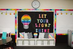 a classroom with a blackboard and colorful decorations on the wall that says let your light shine