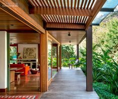 a wooden walkway leading to an outdoor living room and dining area on the other side of the house