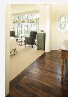 a bedroom with wood flooring and white walls in the background is an open door leading to another room