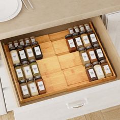 an overhead view of spices in wooden trays on a counter top with plates and utensils