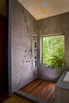 a bathroom with a tub, shower head and wooden flooring next to a window