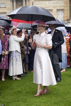 the queen and prince are standing under umbrellas in front of people on the grass