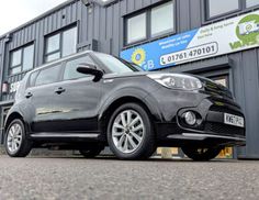 a small black car parked in front of a building