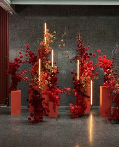 four red vases filled with flowers on top of a floor