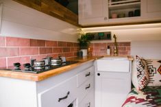 a small kitchen with white cabinets and pink tile backsplash, wood counter tops