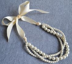 I make the necklace to use 6mm and 10mm ivory glass pearls and ivory ribbon.This beautiful necklace has 9.25" of pearls with 17" of ribbon on each side ,It ties at the top, so is completely adjustable and perfect to grow with little ones. The ribbon has been treated to not fray at the ends.IT is good necklace for your great wedding. I can make different type necklace to your requirements,Please feel free to contact me if you have any question. matches bracelet: https://www.etsy.com/listing/25071 Unique Pearl Necklace, Ivory Pearl Necklace, Real Pearl Necklace, Pearl Jewelry Design, Ivory Earrings, Vintage Jewlery, Ribbon Wedding, Ribbon Necklace, Necklace Ideas