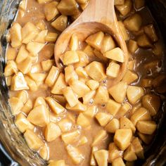 a wooden spoon in a slow cooker filled with cooked potatoes and gravy