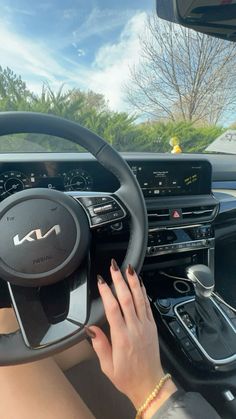 a woman driving a car with her hands on the steering wheel and dashboard controls in front of her