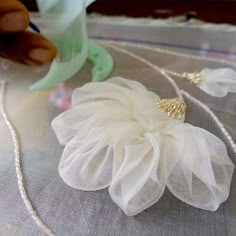 a white flower sitting on top of a table next to a green vase and some beads