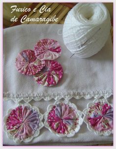 some pink and white crocheted flowers on a table next to a ball of yarn