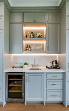 a kitchen with gray cabinets and white counter tops, an oven in the middle is lit by recessed lighting