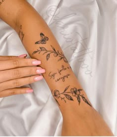 a woman's arm with flowers and butterflies on it, while she is laying down