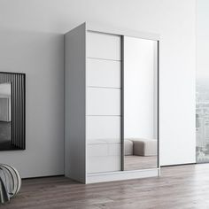 an empty room with white walls and wooden flooring has a large mirror on the wall