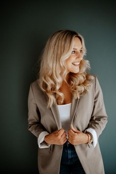 a woman standing in front of a wall with her hands on her hips and smiling