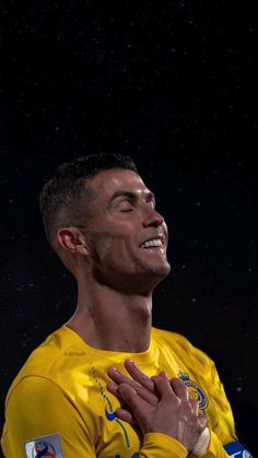 a soccer player is smiling and holding his hands together while looking up at the sky