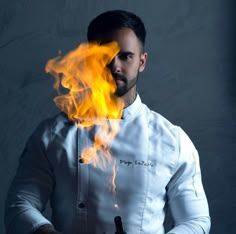 a man in a chef's coat with flames coming out of his hands