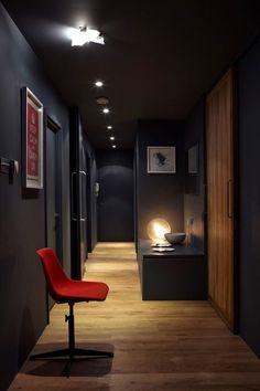 a red chair sitting on top of a hard wood floor next to a black wall