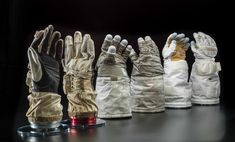 five pairs of gloves are lined up in a row on a black surface, with one glove folded over the other