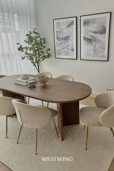 a dining room table with chairs around it and two pictures on the wall behind it