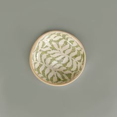 a green and white bowl sitting on top of a gray table next to a wall