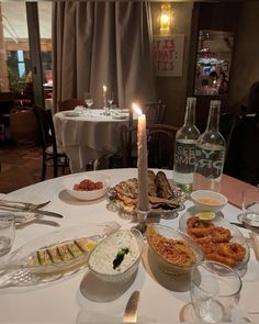 a table topped with lots of food next to a bottle of wine and two glasses