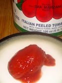 a jar of tomato paste next to a bowl of tomatoes