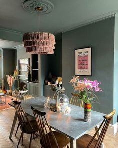 a dining room table with chairs and flowers in vases on the top of it