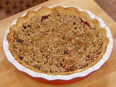 a pie sitting on top of a wooden table covered in crumbly toppings