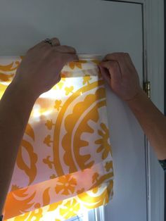 a person is holding up a yellow and white curtain