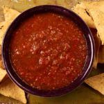 a bowl of salsa with tortilla chips on the side