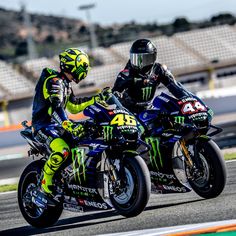 two people on motorcycles are racing around the track, one is wearing a green and black helmet