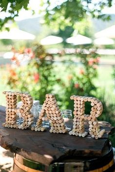 the letters are made out of beads on top of a wooden table with an umbrella in the background