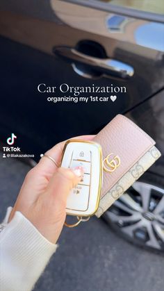 a person holding a cell phone in front of a car with the caption cat organization organizing my 1st car