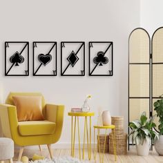 a living room with three chairs and four playing cards on the wall, one yellow chair