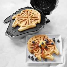 two waffles with blueberries are on a plate next to a toaster