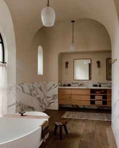 a bath room with a tub a sink and a large mirror on the wall above it